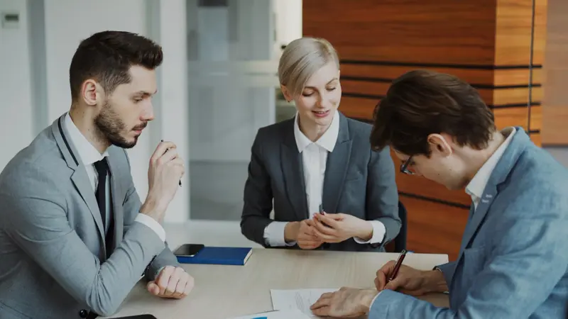 Pessoas assinando um contrato numa mesa de reunião