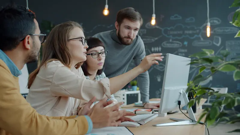 Equipe comercial apontando para a tela do computador
